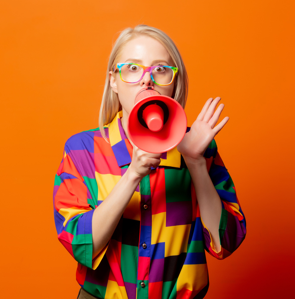 Style blonde in 90s clothes and rainbow glasses with megaphone